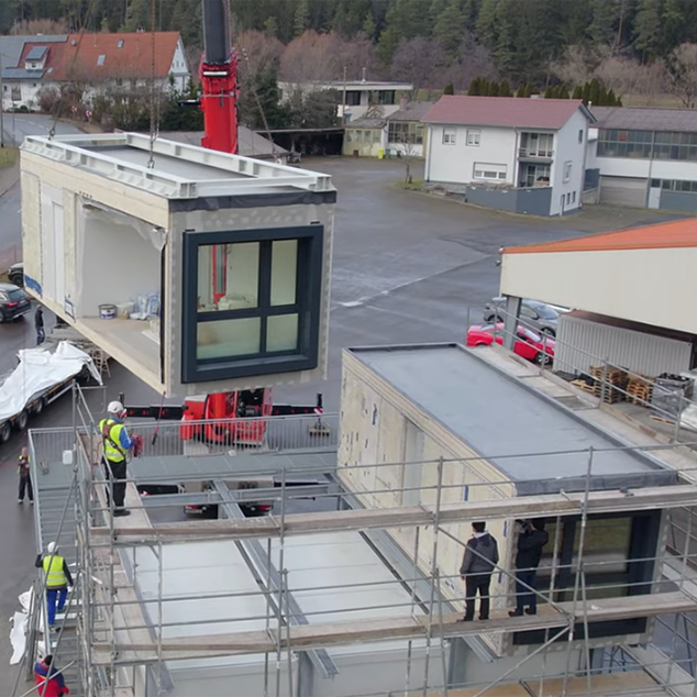 Kran hebt ein vorgefertigtes XSCUBES-Wohnmodul bei der Montage